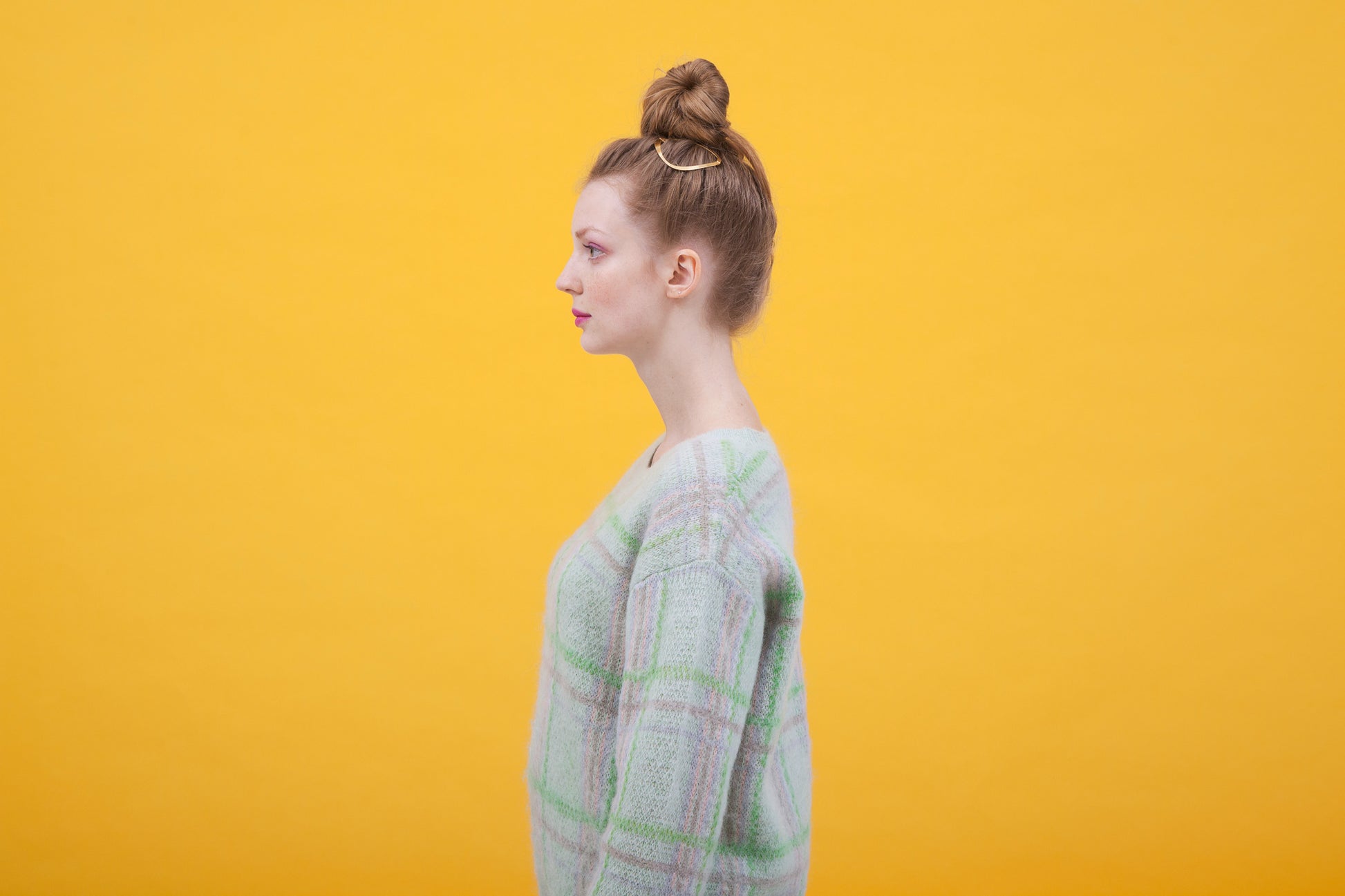 Side view of model Anastasia wearing a top knot with designer hair clip BARBARA as decorative accent
