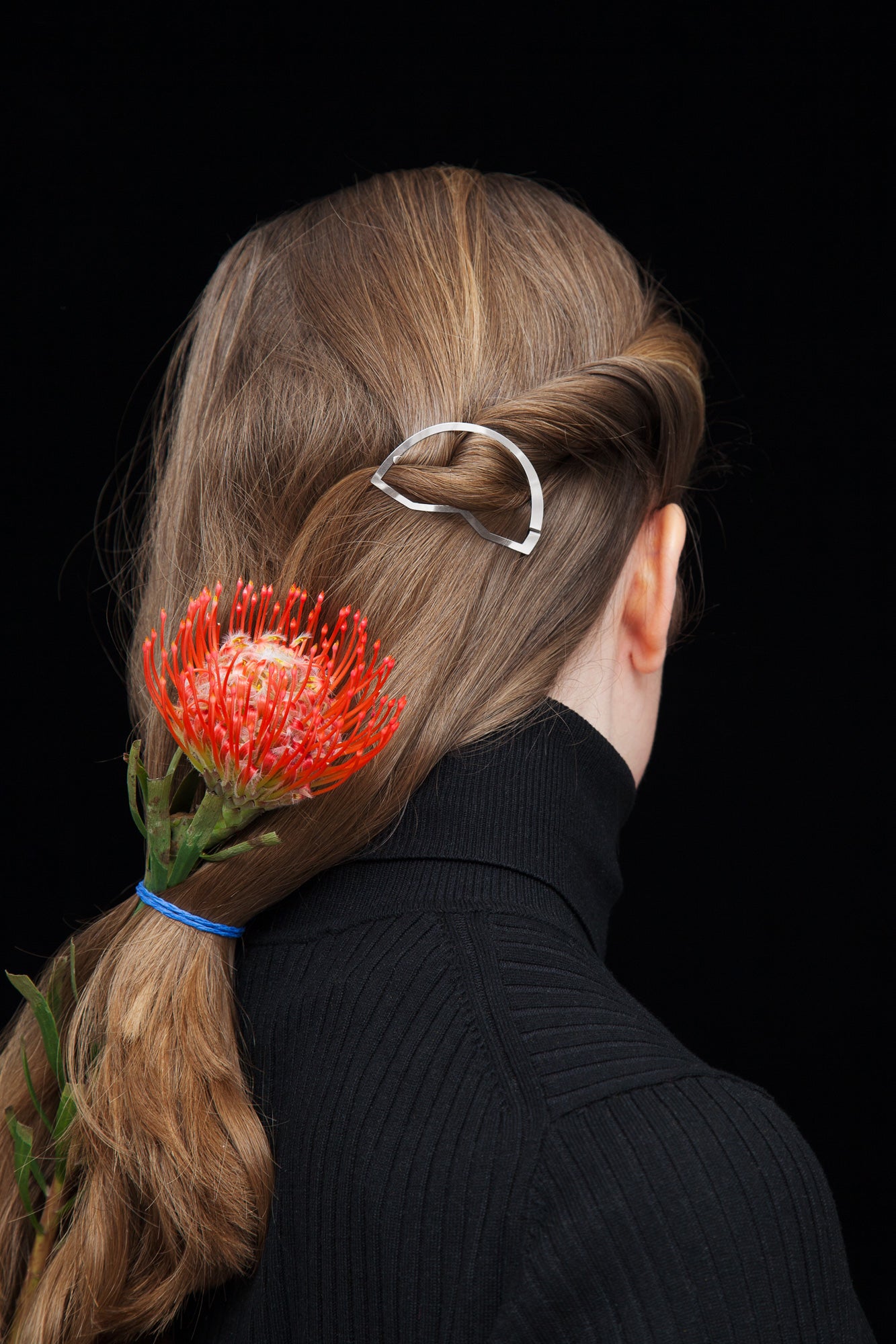 back view of model with hair hair in a low ponytail stayled with a flower and the designer hair clip CYNARA by CLINQ